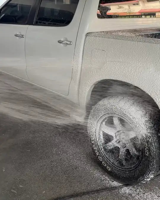 A wheel being covered in foam with a pressure washer
