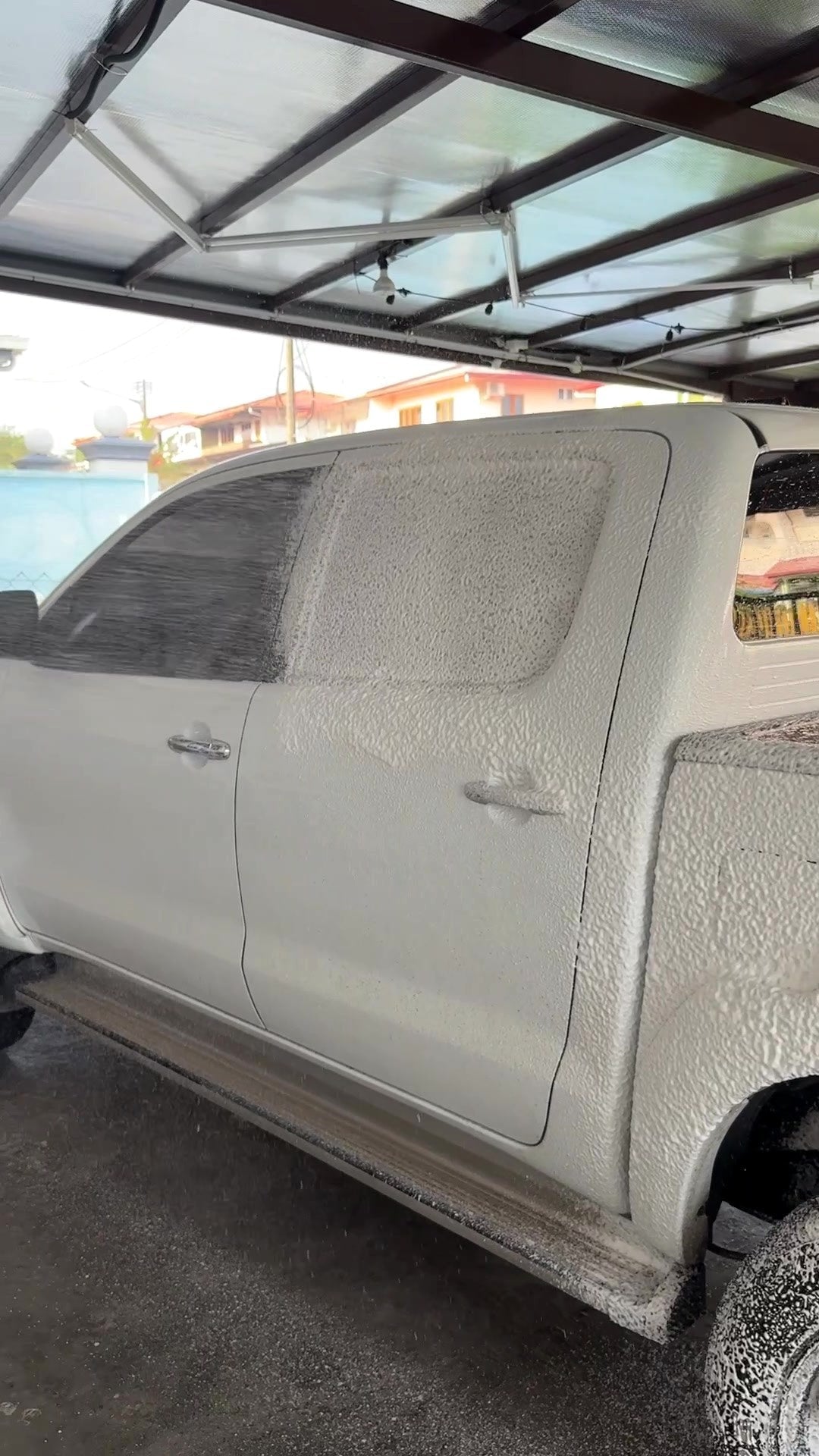 Kereta diselaputi snow foam di bawah porch di Bintulu